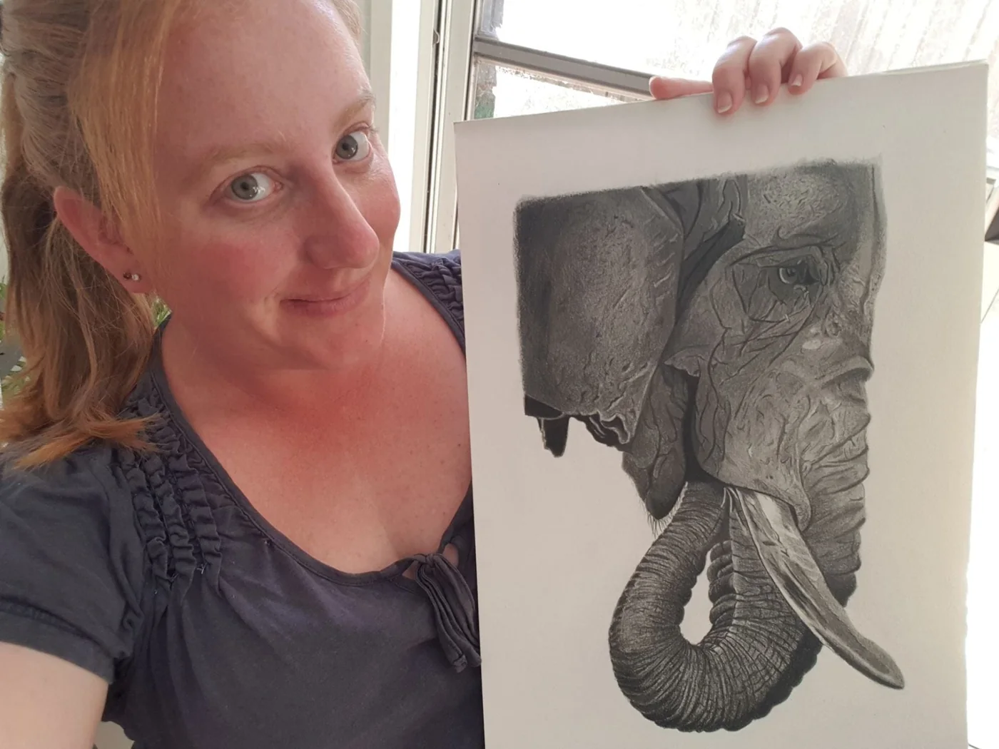 Portrait beside a detailed pencil drawing of an elephant